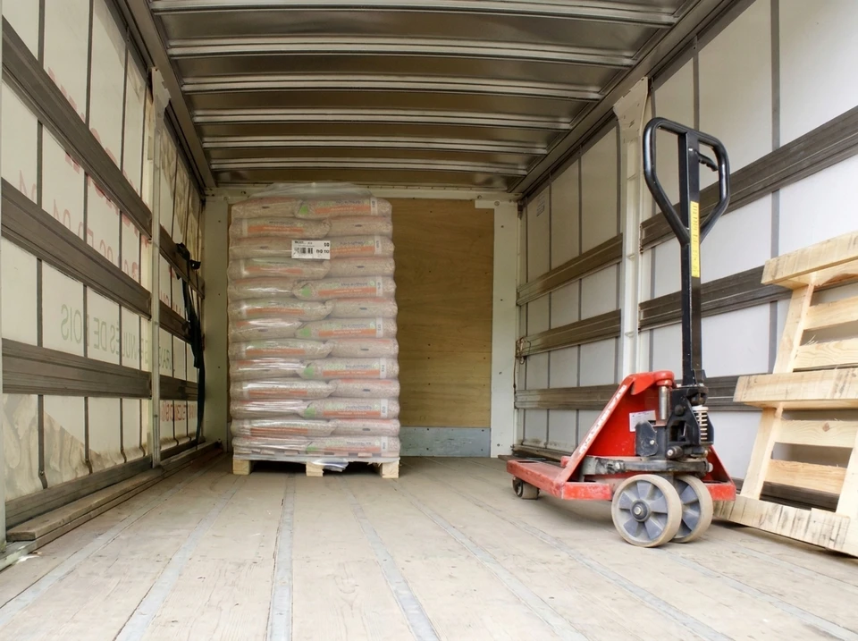 Palettes de granulés de bois en sacs transparents empilés, stockées en extérieur